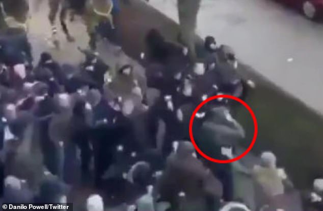 A fan clutches his face after appearing to be hit in the face with a weapon by another supporter